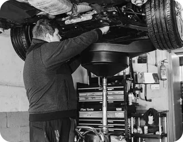 A Meadowfield technician draining engine oil from a car on the ramp